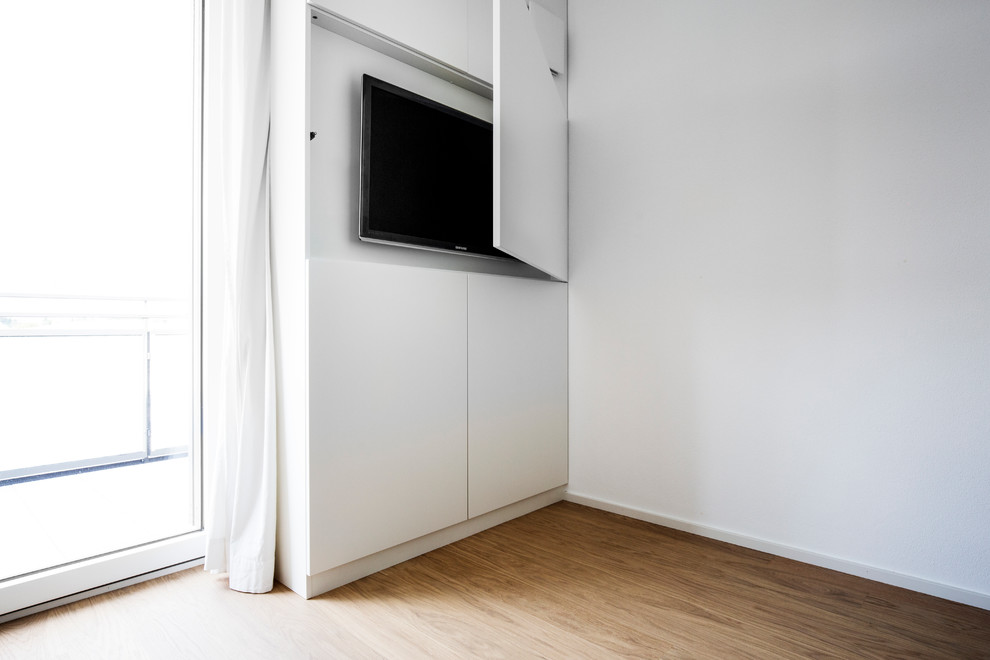 Ejemplo de salón con rincón musical abierto contemporáneo de tamaño medio con paredes blancas, suelo de madera en tonos medios, televisor retractable y suelo marrón