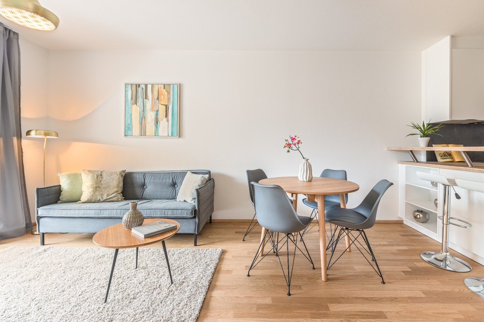 Kleines, Repräsentatives, Offenes Nordisches Wohnzimmer ohne Kamin mit weißer Wandfarbe, braunem Holzboden, freistehendem TV und braunem Boden in Köln