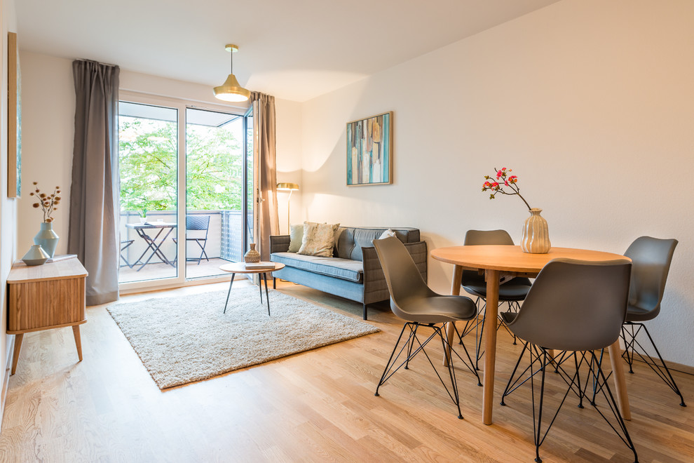 This is an example of a small scandi formal open plan living room in Cologne with white walls, medium hardwood flooring, no fireplace, a freestanding tv and brown floors.