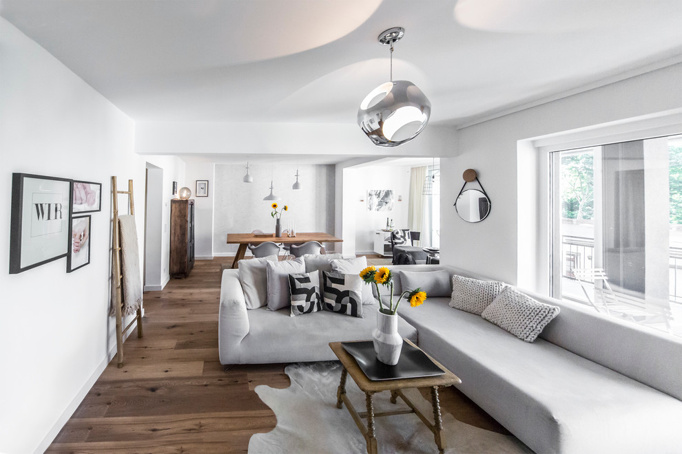 На фото: большая открытая гостиная комната в скандинавском стиле с белыми стенами и паркетным полом среднего тона без камина с