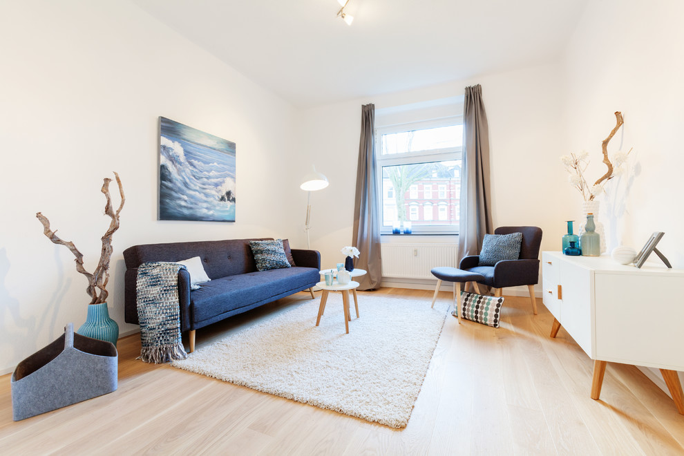 Example of a mid-sized danish enclosed light wood floor living room design in Essen with white walls, no fireplace and no tv