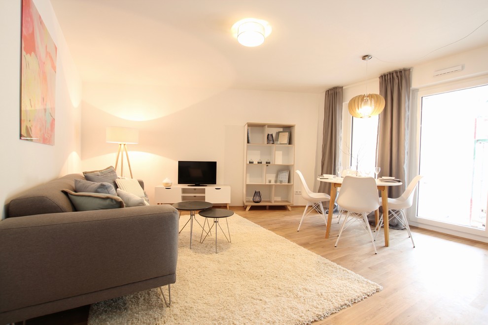 Large scandi enclosed games room in Frankfurt with white walls, light hardwood flooring, no fireplace, a freestanding tv and beige floors.