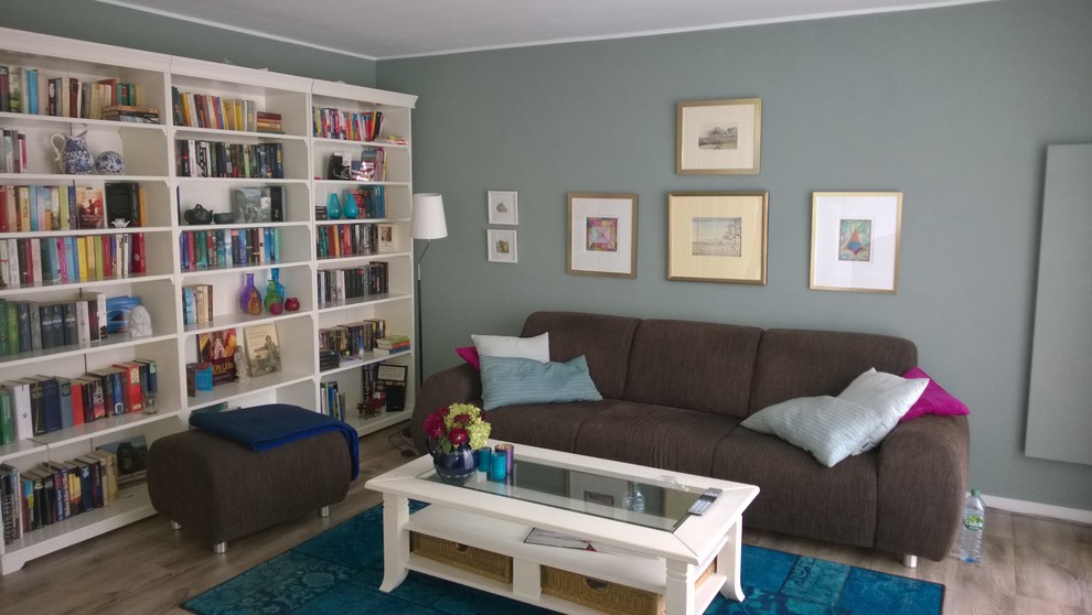 Modelo de sala de estar abierta campestre de tamaño medio sin chimenea con televisor colgado en la pared, paredes verdes y suelo vinílico