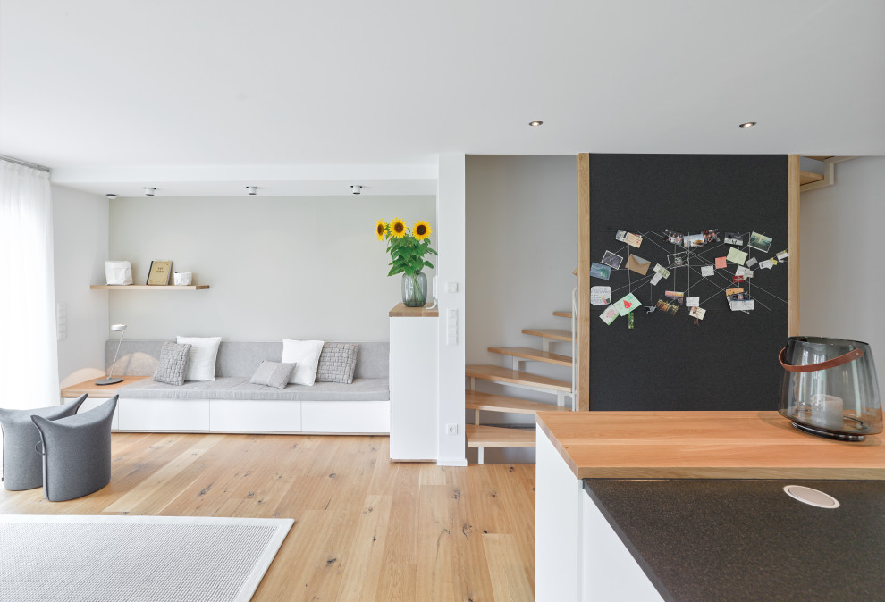 Imagen de salón abierto actual de tamaño medio con paredes blancas, suelo de madera en tonos medios y suelo marrón