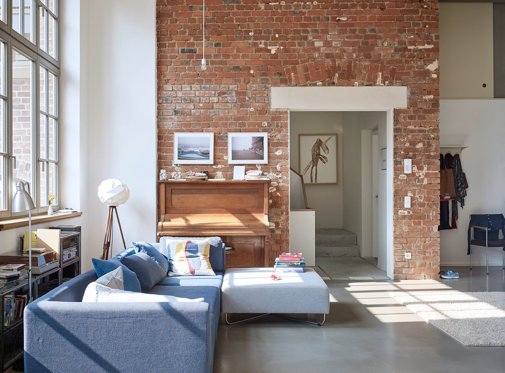 На фото: гостиная комната среднего размера в стиле лофт с музыкальной комнатой, белыми стенами, бетонным полом и синим диваном с