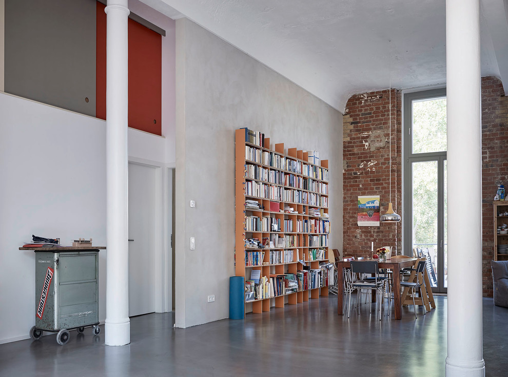 На фото: огромная двухуровневая гостиная комната в стиле лофт с с книжными шкафами и полками и серыми стенами