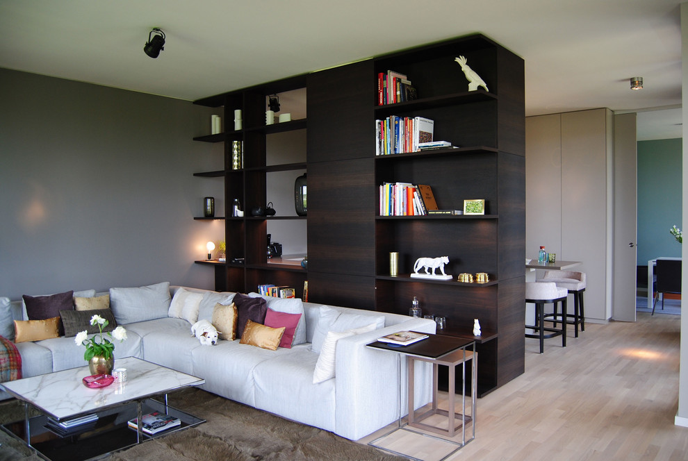 Modelo de biblioteca en casa abierta contemporánea extra grande con paredes grises y suelo de madera clara