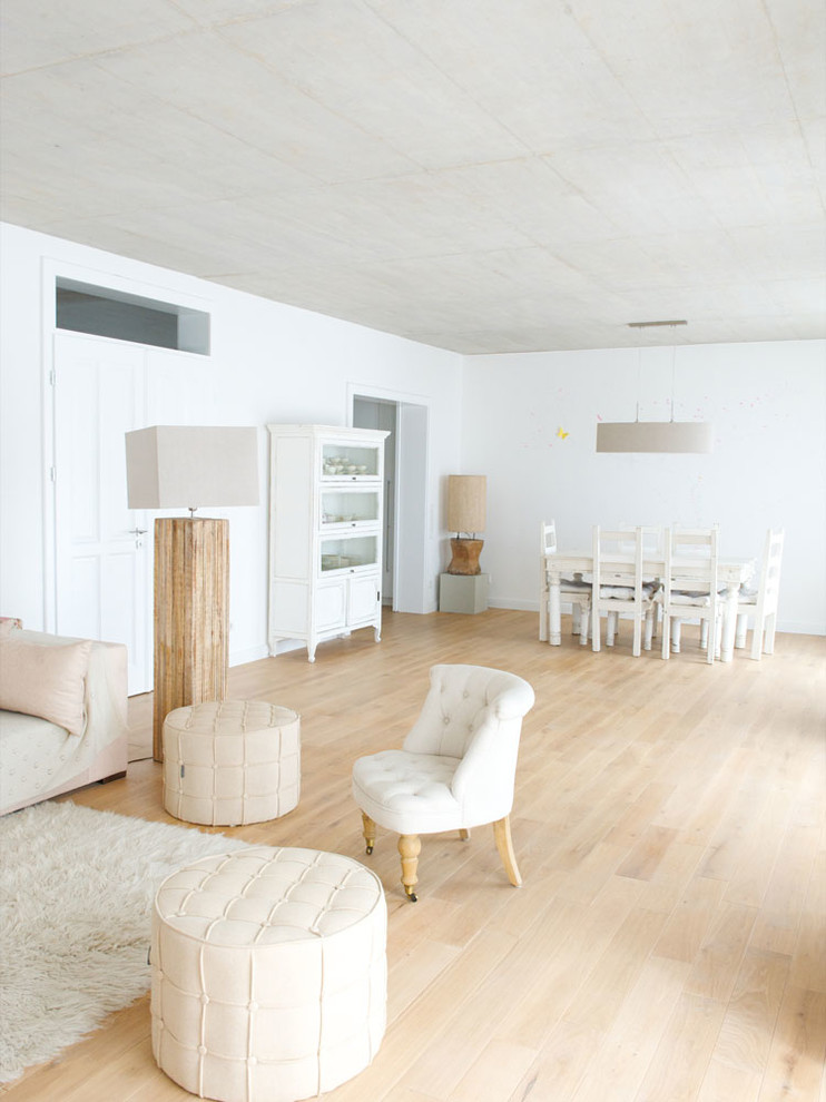 Пример оригинального дизайна: большая открытая гостиная комната в стиле кантри с белыми стенами, светлым паркетным полом, печью-буржуйкой и фасадом камина из штукатурки