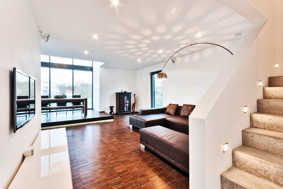 Großes, Offenes Modernes Wohnzimmer ohne Kamin mit weißer Wandfarbe, dunklem Holzboden und TV-Wand in Frankfurt am Main