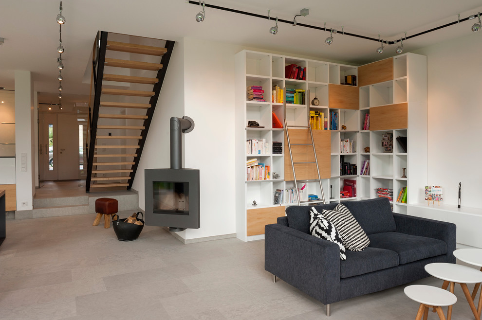 Стильный дизайн: открытая гостиная комната в современном стиле с с книжными шкафами и полками, белыми стенами, угловым камином, полом из травертина и серым полом - последний тренд