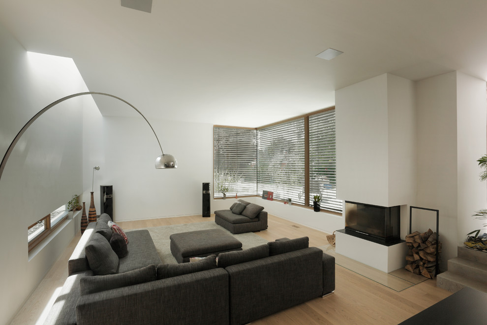 Geräumiges, Fernseherloses, Offenes Modernes Wohnzimmer mit weißer Wandfarbe, hellem Holzboden, verputzter Kaminumrandung und Eckkamin in Frankfurt am Main