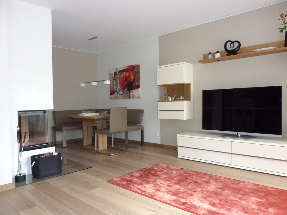 Mittelgroßes, Offenes Klassisches Wohnzimmer mit beiger Wandfarbe, hellem Holzboden, Eckkamin, verputzter Kaminumrandung und freistehendem TV in Frankfurt am Main
