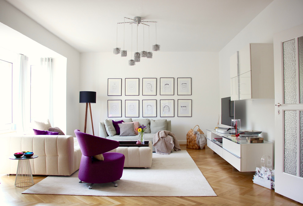 Modernes Wohnzimmer mit weißer Wandfarbe, braunem Holzboden, freistehendem TV und braunem Boden in Frankfurt am Main
