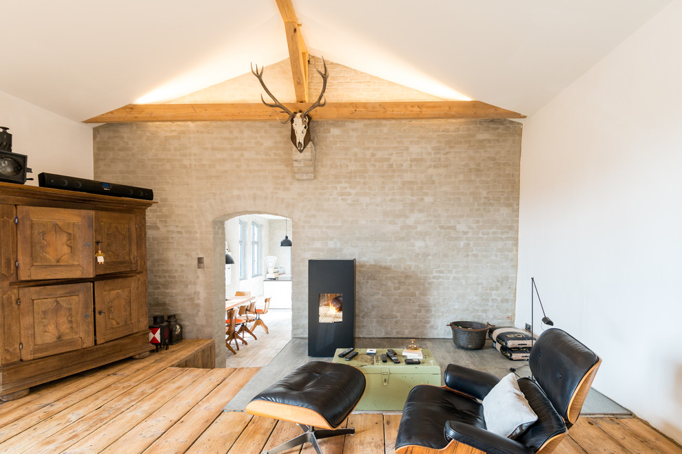Ejemplo de sala de estar tipo loft actual con todas las chimeneas, suelo de madera en tonos medios y paredes blancas