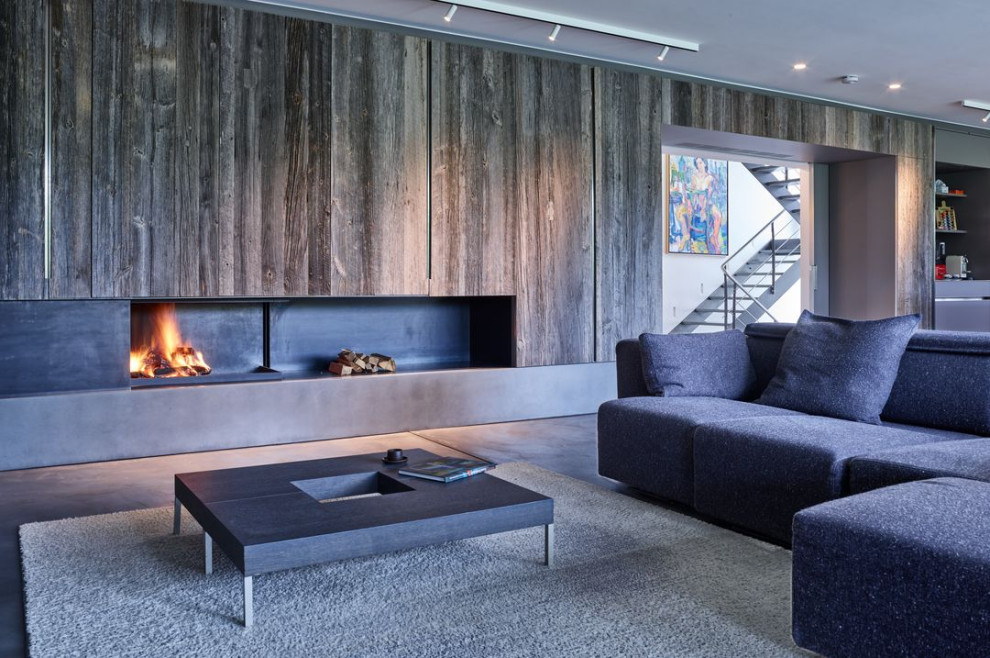 Imagen de salón para visitas abierto actual con suelo de cemento, marco de chimenea de metal y suelo gris