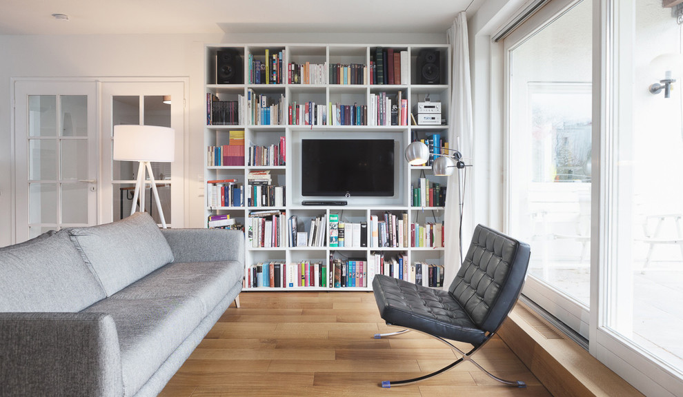 Offenes Skandinavisches Wohnzimmer mit weißer Wandfarbe, hellem Holzboden und Multimediawand in München