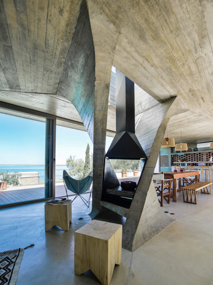Modern inredning av ett mycket stort allrum med öppen planlösning, med ett finrum, grå väggar, en hängande öppen spis och betonggolv