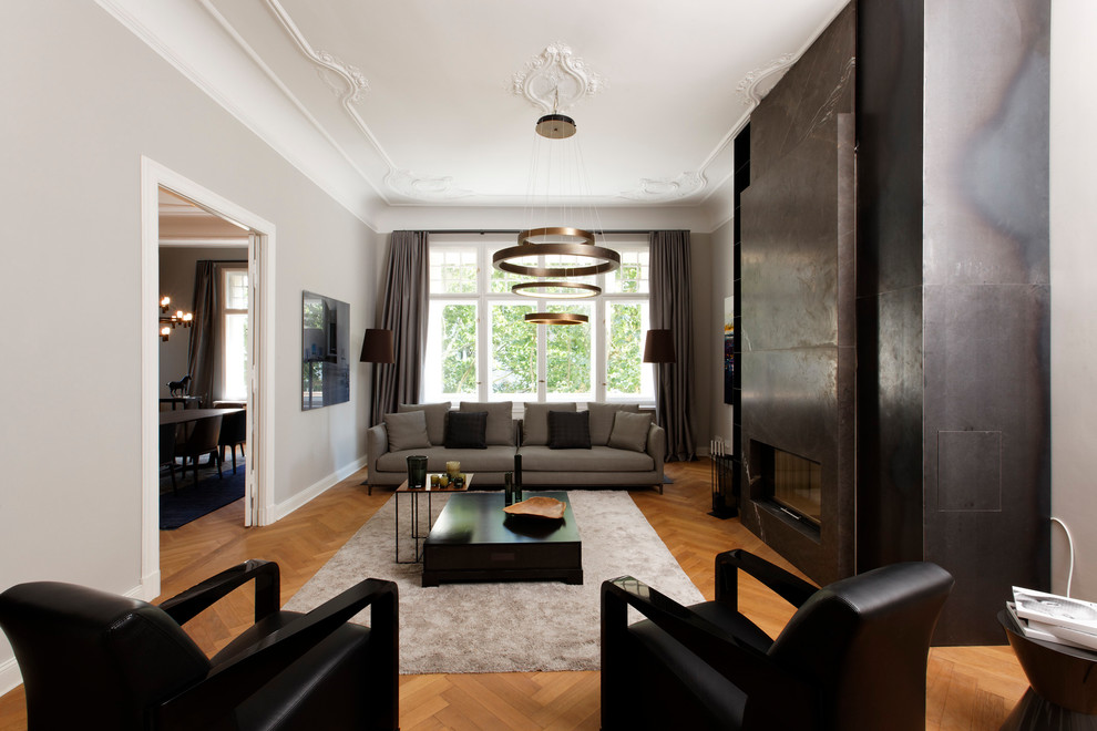 Пример оригинального дизайна: изолированная гостиная комната среднего размера в современном стиле с серыми стенами, паркетным полом среднего тона, горизонтальным камином, фасадом камина из камня и коричневым полом