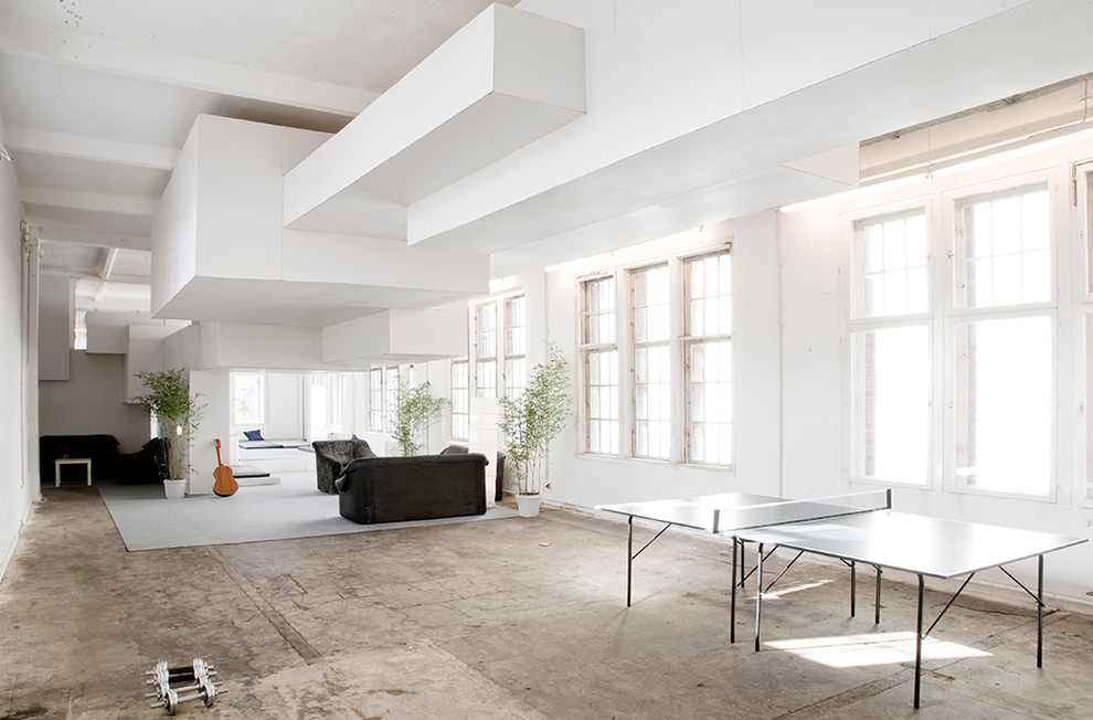 Geräumiges Wohnzimmer ohne Kamin mit weißer Wandfarbe und Betonboden in Berlin