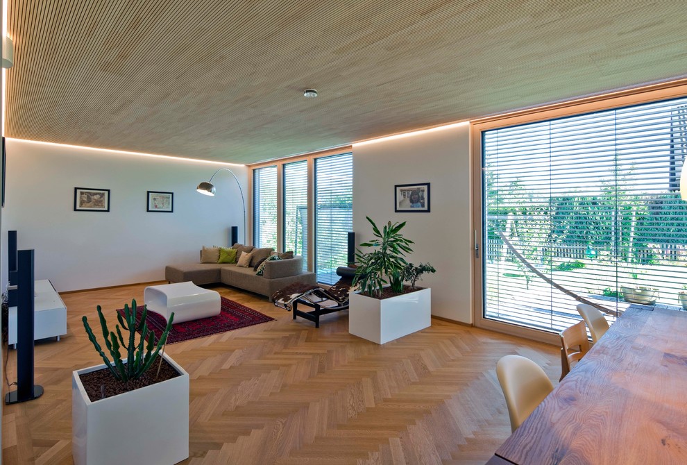 Immagine di un soggiorno minimal di medie dimensioni e aperto con pareti bianche, pavimento in legno massello medio, TV a parete e pavimento marrone