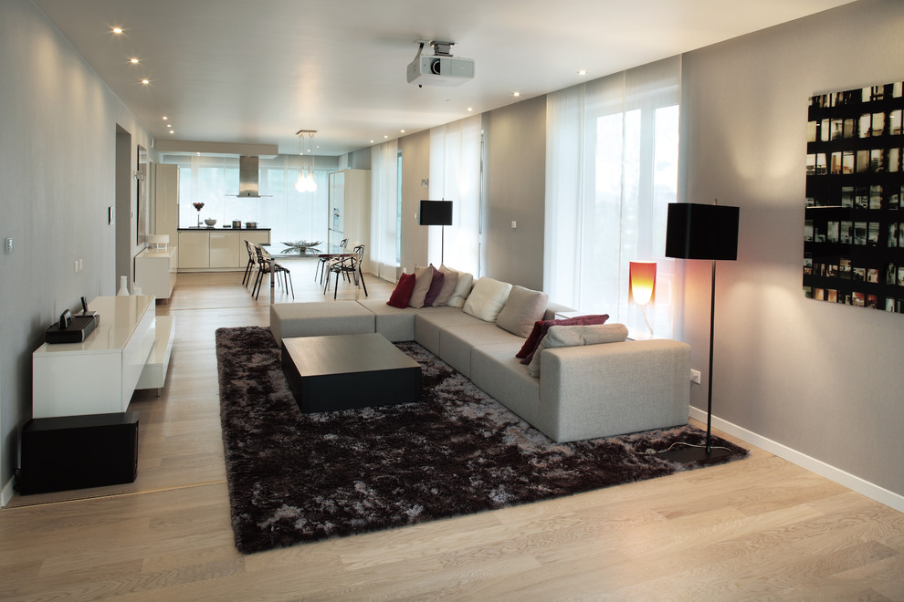 На фото: большая открытая гостиная комната в современном стиле с серыми стенами и светлым паркетным полом без камина, телевизора