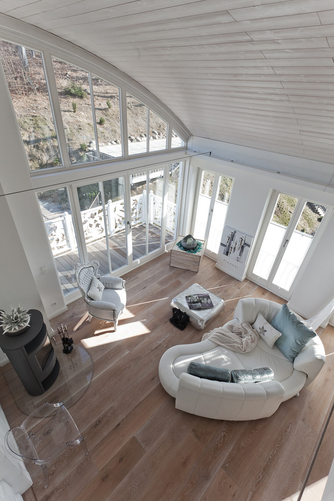 Ejemplo de sala de estar tipo loft actual grande con paredes blancas, suelo de madera clara, chimenea de esquina, marco de chimenea de metal y televisor independiente