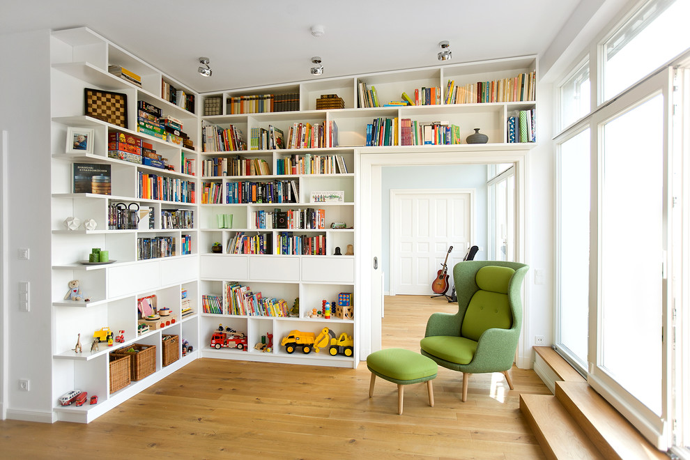 Imagen de biblioteca en casa cerrada actual de tamaño medio sin chimenea y televisor con paredes blancas y suelo de madera en tonos medios