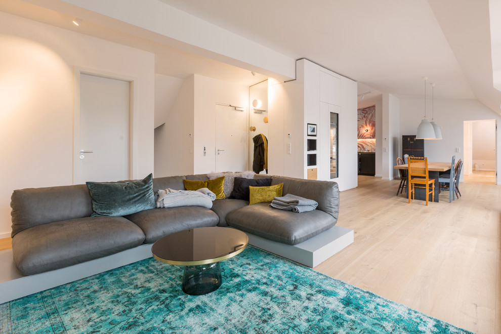 Offenes, Großes Modernes Wohnzimmer ohne Kamin mit weißer Wandfarbe, hellem Holzboden, Eck-TV und beigem Boden in München