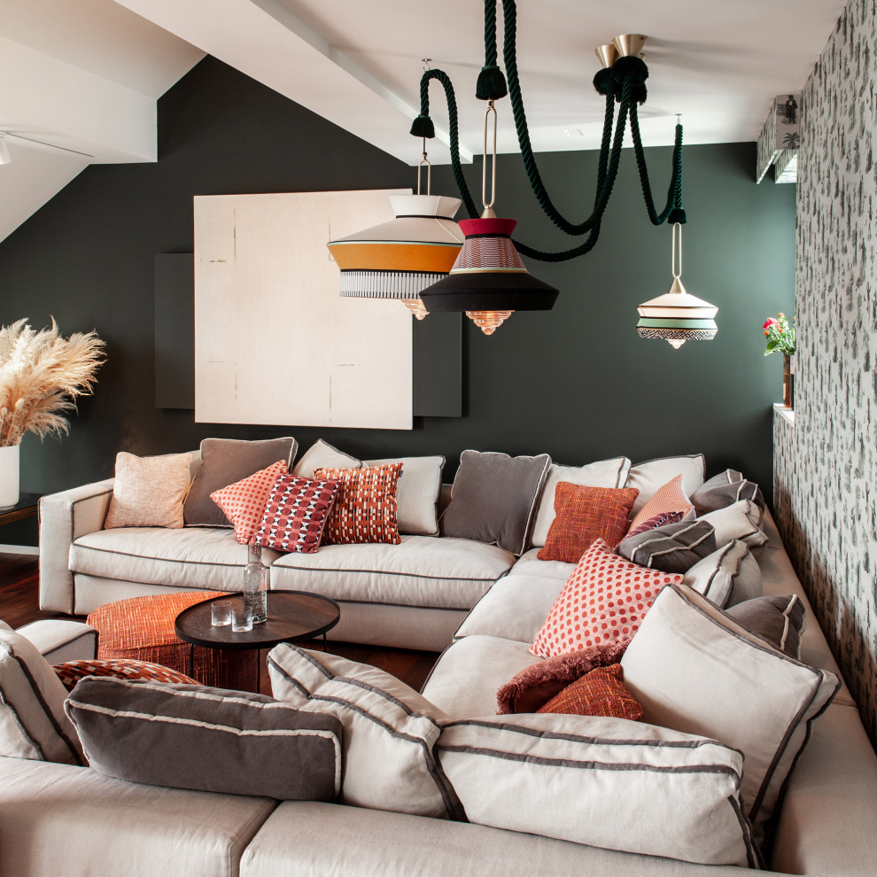 Modelo de sala de estar abierta ecléctica extra grande con paredes verdes, suelo de madera en tonos medios, televisor retractable, suelo marrón, bandeja y papel pintado