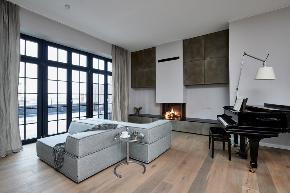 Идея дизайна: большая открытая гостиная комната в современном стиле с серыми стенами, паркетным полом среднего тона, печью-буржуйкой, фасадом камина из штукатурки, коричневым полом и телевизором на стене