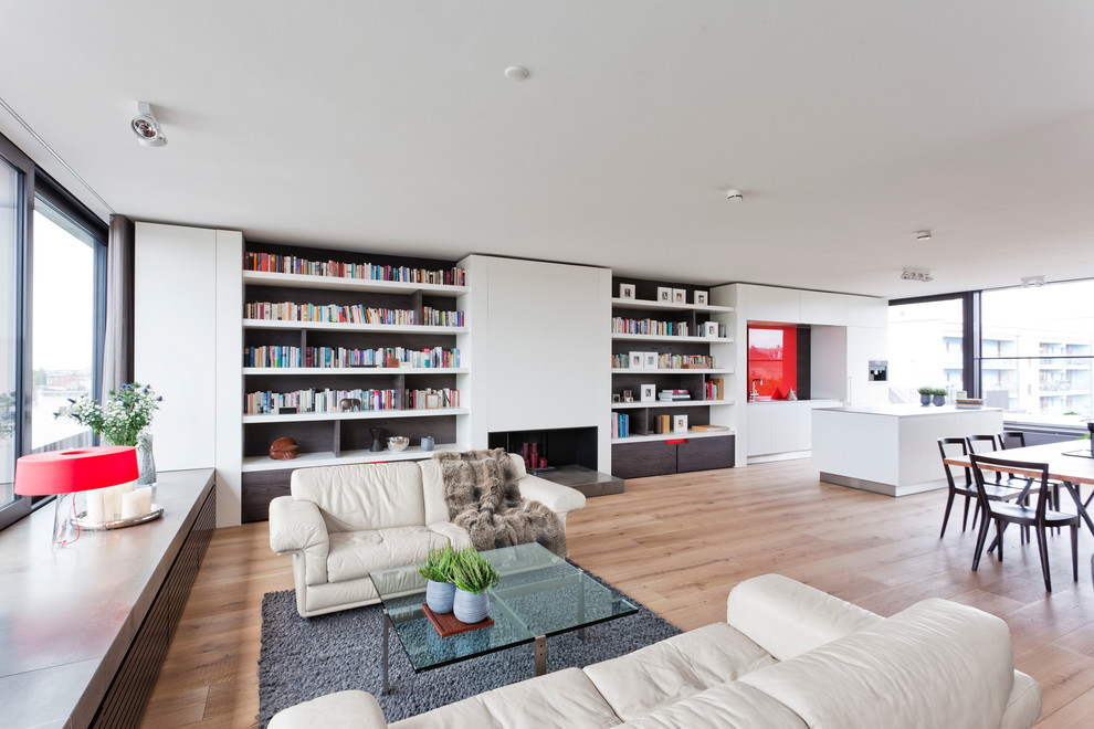 Inspiration för stora moderna vardagsrum, med ett bibliotek, vita väggar, ljust trägolv och en standard öppen spis