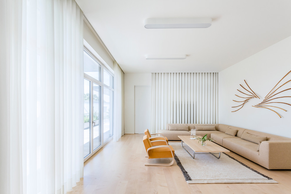 Großes, Offenes Modernes Wohnzimmer mit weißer Wandfarbe, hellem Holzboden und verstecktem TV in Köln
