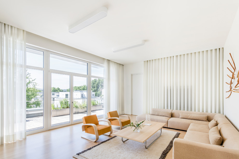 Idée de décoration pour une grande salle de séjour minimaliste ouverte avec un mur blanc, parquet clair et un téléviseur dissimulé.