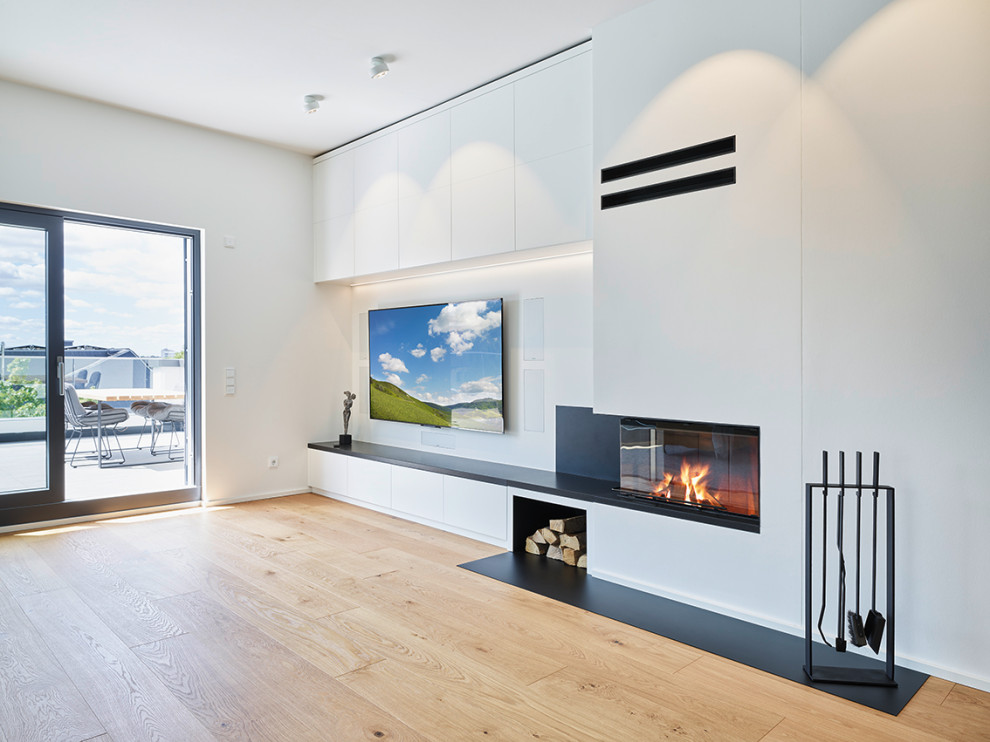 Imagen de salón abierto y gris y blanco actual extra grande con paredes blancas, suelo de madera en tonos medios, chimenea de esquina, televisor colgado en la pared y suelo beige