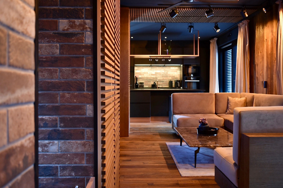 Стильный дизайн: гостиная комната в современном стиле с красными стенами, деревянным полом, фасадом камина из кирпича и коричневым полом - последний тренд