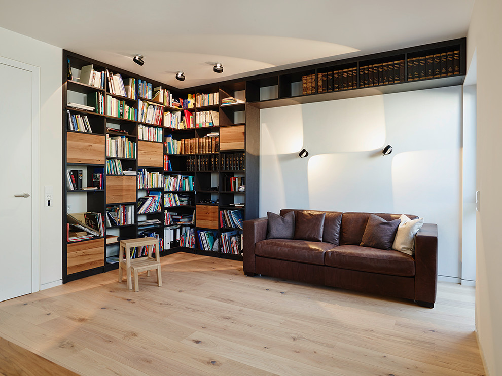 Immagine di un soggiorno contemporaneo chiuso con libreria, pareti bianche, parquet chiaro, nessun camino e nessuna TV
