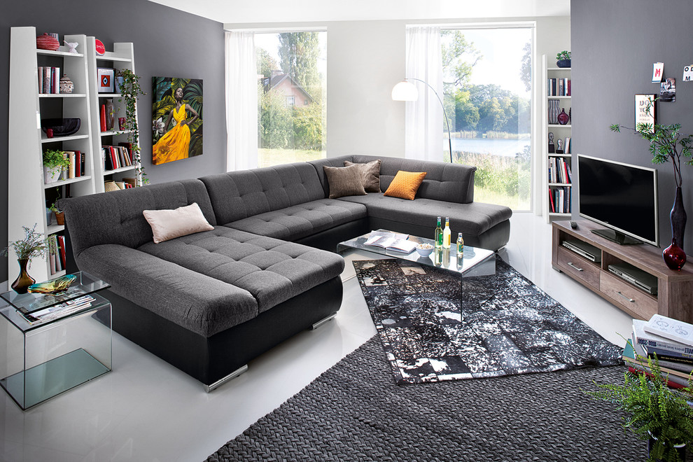 Modelo de sala de estar abierta contemporánea extra grande con paredes grises, moqueta y televisor en una esquina