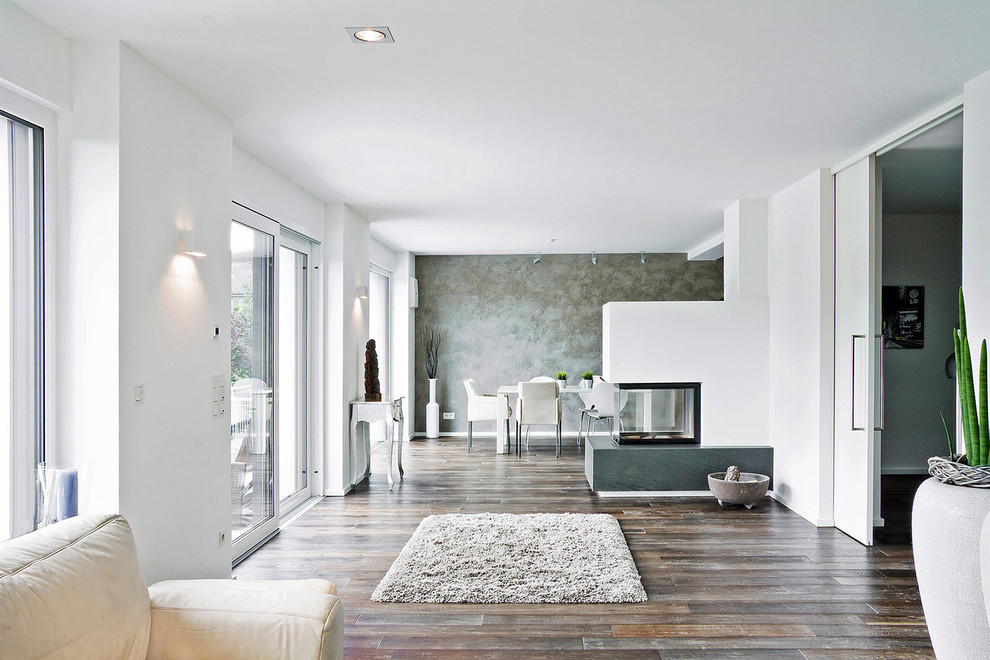 Großes, Offenes Modernes Wohnzimmer mit weißer Wandfarbe, dunklem Holzboden, Tunnelkamin und verputzter Kaminumrandung in Dortmund