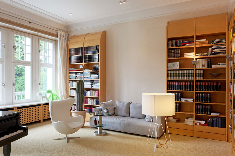 Стильный дизайн: изолированная гостиная комната в современном стиле с с книжными шкафами и полками, белыми стенами и ковровым покрытием - последний тренд