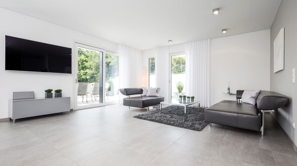 Immagine di un ampio soggiorno minimalista chiuso con pareti bianche, pavimento in gres porcellanato, nessun camino, TV a parete e pavimento grigio
