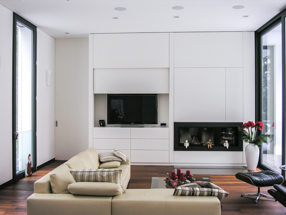 Modernes Wohnzimmer mit weißer Wandfarbe, braunem Holzboden, Gaskamin, verstecktem TV und braunem Boden in Frankfurt am Main