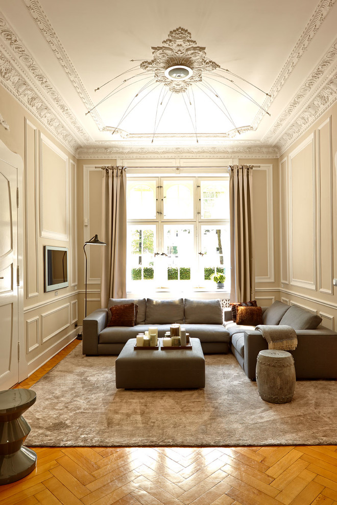 Ejemplo de salón para visitas cerrado clásico grande sin chimenea con paredes beige, televisor colgado en la pared y suelo de madera en tonos medios