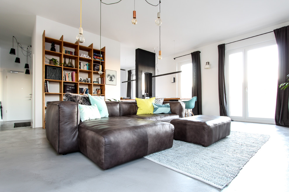 На фото: открытая гостиная комната среднего размера в современном стиле с бетонным полом и телевизором на стене с