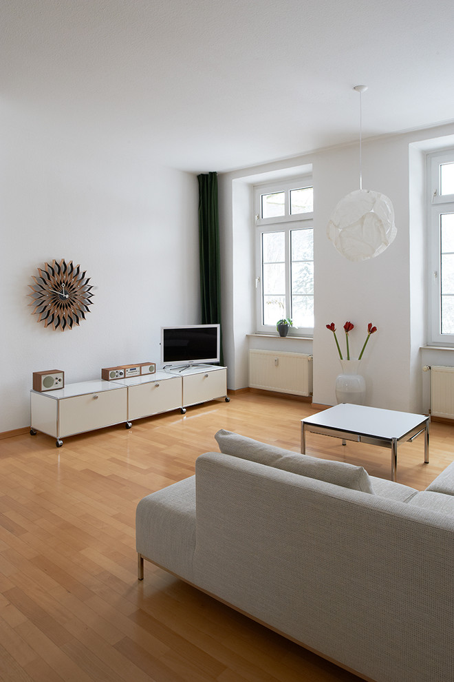 На фото: открытая гостиная комната среднего размера в классическом стиле с белыми стенами, паркетным полом среднего тона и отдельно стоящим телевизором с
