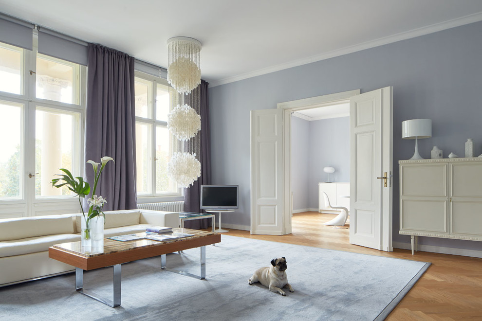 Modelo de sala de estar cerrada tradicional grande sin chimenea con suelo de madera en tonos medios, televisor independiente y paredes púrpuras