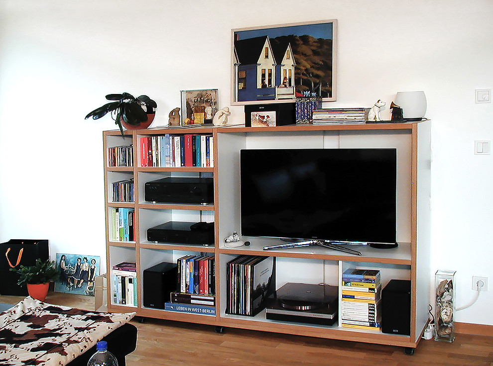 Offenes Modernes Wohnzimmer mit weißer Wandfarbe, hellem Holzboden und freistehendem TV in Berlin
