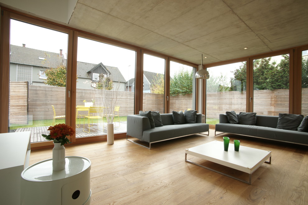 Kleines, Repräsentatives Modernes Wohnzimmer mit weißer Wandfarbe, braunem Holzboden und TV-Wand in Düsseldorf