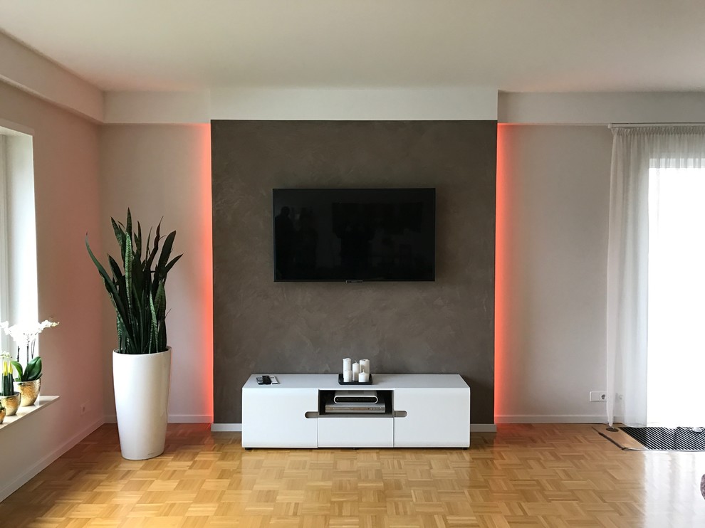 Foto de sala de estar abierta contemporánea de tamaño medio con paredes beige, suelo de madera clara y pared multimedia