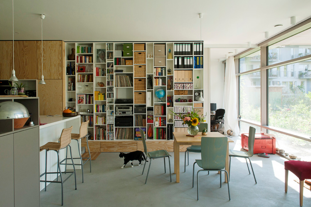 Idee per un soggiorno contemporaneo di medie dimensioni e aperto con libreria, pavimento in cemento, pareti bianche, nessun camino e nessuna TV