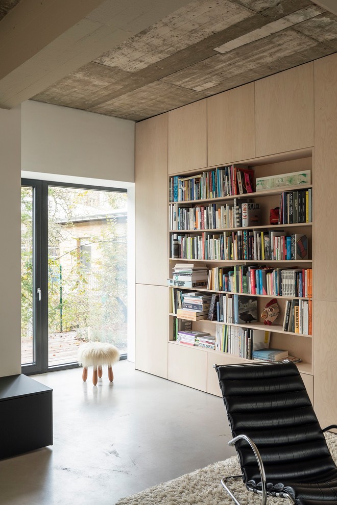 Offene, Mittelgroße, Fernseherlose Moderne Bibliothek mit weißer Wandfarbe, Betonboden und grauem Boden in Berlin